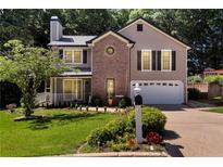 Charming two-story home featuring a manicured lawn, brick accents, and an attached two-car garage at 1481 Howard Way, Lawrenceville, GA 30043