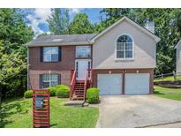 Charming two-story home with brick and stucco exterior, front yard, and two-car garage at 999 Brecken Ln, Lithonia, GA 30058