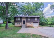 Charming home with a front lawn and driveway, framed by mature trees providing shade at 1966 Snapfinger Rd, Decatur, GA 30035
