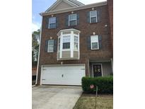 Charming brick townhome featuring a front entry garage and a well-maintained yard with lush greenery at 4210 Chatham Ridge Drive Dr, Buford, GA 30518