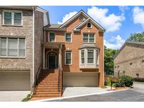 Charming brick townhouse with a front-facing garage and inviting staircase to the front door at 5575 Julian Pl, Atlanta, GA 30342