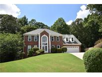 Charming brick home with arched window, well-maintained lawn, and an attached two car garage at 1858 De Winton Pl, Lawrenceville, GA 30043