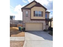 Two story home featuring a two-car garage, brick accents, a manicured lawn, and a concrete driveway at 2423 Turnbury Glen Walk, Snellville, GA 30078