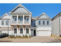 Charming two-story home with white brick, gray siding, a balcony, and a two-car garage at 89 Batten Board Way, Woodstock, GA 30189