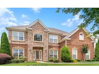 Elegant two-story brick home featuring a stone facade, arched entryway, and beautifully landscaped front yard at 3843 Dragon Fly Ln, Loganville, GA 30052