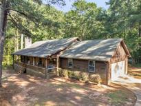 Beautiful single-story wood home featuring a charming front porch and attached garage nestled in a wooded lot at 1000 Coan Dr, Locust Grove, GA 30248