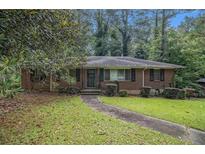 Charming brick home with a landscaped front yard, mature trees, and a paved walkway leading to the front door at 1206 Tuckawanna Sw Dr, Atlanta, GA 30311