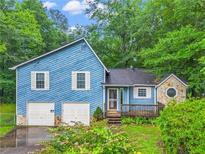 Quaint two-story blue home with white trim, a two-car garage, and a stone accented side entrance at 2419 Anderson Mill Rd, Austell, GA 30106