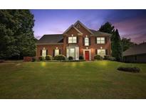 Charming two-story brick home with a well-manicured lawn and inviting red front door at 3520 Mystic Dr, Buford, GA 30519