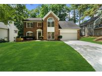 Charming brick home features a manicured lawn, a two-car garage and beautiful curb appeal at 11660 Windbrooke Way, Johns Creek, GA 30005