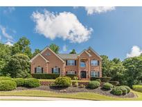 Beautiful brick home featuring mature landscaping and manicured lawn under a bright blue sky at 3202 Lucky Pl, Conyers, GA 30013