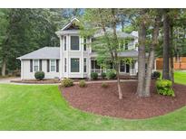 Charming two-story home with landscaped yard and inviting front porch nestled among mature trees at 1655 Oak Crest Ct, Marietta, GA 30066