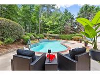 Inviting backyard pool with lush landscaping, patio seating, and tranquil setting at 1065 Beacon Hill Xing, Alpharetta, GA 30005