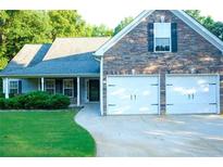 Charming home featuring a stone facade, two-car garage, well-maintained lawn, and covered front porch at 85 Lamar Ln, Covington, GA 30016