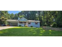 Charming, light blue single-Gathering home with a well-manicured front yard and covered parking area at 2357 Whitehouse Rd, Dacula, GA 30019