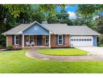 Charming brick home with a well-manicured lawn, inviting front porch, and attached two-car garage at 1402 Mclendon Dr, Decatur, GA 30033