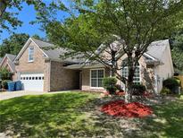 Charming brick home with a well-manicured lawn, mature tree, and a two-car garage at 1570 Jami Hollow Way, Lawrenceville, GA 30043