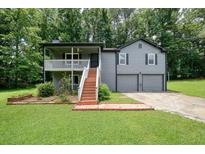 Charming two-story home with gray siding, a front porch, and a two-car garage nestled among lush trees at 174 Village Dr, Hiram, GA 30141