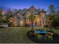 Elegant stone home with manicured lawn, water feature and palm trees at dusk at 1310 Settles Rd, Suwanee, GA 30024