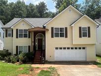 Charming two-story home with a white garage door, brown shutters and light yellow siding at 355 Tambec Nw Trce, Lilburn, GA 30047