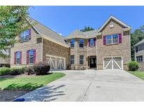 Inviting two-story brick home with a two-car garage and lush green lawn at 4395 Wildbrooke Pkwy, Cumming, GA 30041