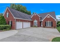 Charming brick home featuring a two-car garage, well-manicured lawn, and classic architectural details at 5176 Ashbury Manor Ln, Sugar Hill, GA 30518