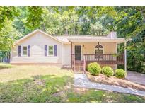 Inviting single-story home featuring a charming front porch, well-maintained lawn, and surrounded by lush trees at 356 Waterway Trl, Powder Springs, GA 30127