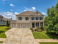Beautiful brick home features a three-car garage and a well-manicured front yard, all under a bright, sunny sky at 4430 Alister Park Dr, Cumming, GA 30040