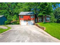 Charming home boasts a stone facade, two-car garage, and a well-maintained front yard, all nestled on a tree-lined lot at 1030 Chapman Ln, Stone Mountain, GA 30088