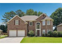 Charming two-story brick home featuring a manicured lawn, two-car garage, and large arched entryway at 775 Gran Heritage Way, Dacula, GA 30019