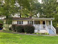 Charming single-story home featuring a cozy front porch and mature trees in a serene, landscaped yard at 1003 Valley Se Dr, Smyrna, GA 30080