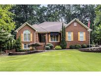 Charming brick home with manicured lawn, mature trees, and yellow shutters at 2525 Fairview Dr, Cumming, GA 30041