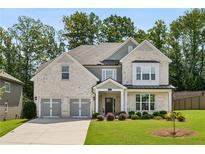 Charming two-story brick home featuring a three-car garage, manicured lawn, and mature landscaping at 614 Denali Dr, Mableton, GA 30126