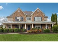 Traditional two-story brick home featuring a covered front porch and lush landscaping at 1527 Sage Ridge Dr, Marietta, GA 30064
