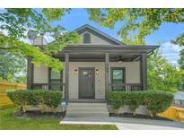 Quaint house featuring a covered front porch with ample seating and manicured shrubs along the walkway at 556 Paines Nw Ave, Atlanta, GA 30318