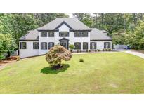 Charming white two-story home with black shutters and lush green lawn at 1887 Chedworth Ct, Stone Mountain, GA 30087