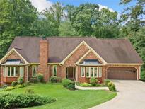 Charming brick home featuring bay windows, attached garage, and lush lawn at 3436 Laurelwood Ne Ct, Roswell, GA 30075