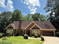 Charming brick home with manicured lawn, mature trees, and attached two-car garage at 3436 Laurelwood Ne Ct, Roswell, GA 30075