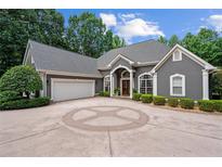 Elegant gray home with a circular driveway and manicured landscaping in a serene, wooded setting at 9125 Patrick Pl, Winston, GA 30187