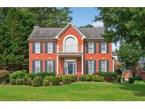 Charming red brick two-story home featuring a beautiful balcony, manicured lawn, and mature landscaping at 2559 Dunhaven Gln, Snellville, GA 30078