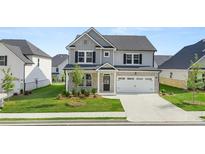 Charming two-story home with grey and white brick exterior, a well-manicured lawn, and a two car garage at 13568 Whitman Lane, Covington, GA 30014
