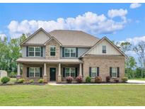 Charming two-story brick home with a covered porch, manicured lawn, and beautiful landscaping at 149 Elkins Blvd, Locust Grove, GA 30248