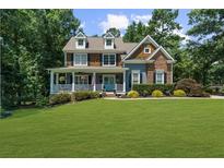 Charming two-story home with a manicured lawn, lush landscaping, and inviting front porch at 4020 High Gables E, Cumming, GA 30041