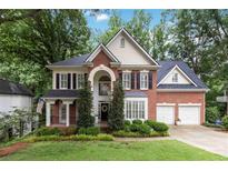 Inviting two-story brick home featuring a manicured lawn, mature trees, and a two-car garage at 2200 Major Loring Sw Way, Marietta, GA 30064