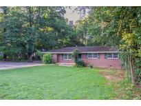 Charming brick home with a lush green lawn and mature trees, offering a serene and inviting curb appeal at 310 Samaritan Dr, Cumming, GA 30040