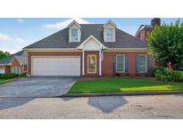 Charming brick home featuring a two-car garage, well-manicured lawn, and an inviting front entrance at 2000 Stockton Walk Ln, Snellville, GA 30078