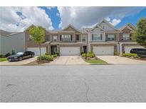 Charming townhomes with brick accents, attached garages, and well-maintained landscaping on a sunny day at 2638 Village Park Bnd, Duluth, GA 30096