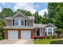 Charming two-story home featuring a two-car garage, a landscaped yard, and a welcoming front porch with an American flag at 1115 Manor Nw Way, Kennesaw, GA 30144