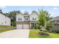 Charming two-story home featuring a manicured lawn, gray siding, and a two-car garage at 5394 Pebblebrook Se Ln, Mableton, GA 30126