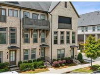 Charming brick townhome with a balcony, manicured landscaping, and inviting curb appeal at 2447 Figaro Dr, Atlanta, GA 30339